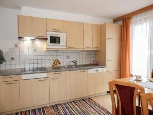 cocina con armarios de madera, fregadero y microondas en Apartment Bergfeld - SIX170 by Interhome, en Spiss