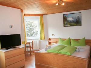 a bedroom with a bed with green pillows and a television at Apartment Helga - TDL113 by Interhome in Tobadill