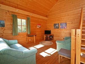 a living room with blue furniture in a log cabin at Holiday Home Haus Fries by Interhome in Unterbergern