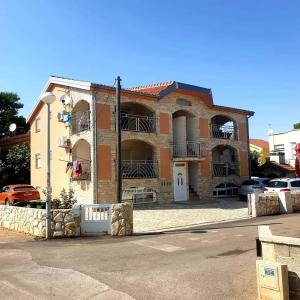 un gran edificio de ladrillo con coches aparcados en un aparcamiento en Apartmani Mujic, en Vir