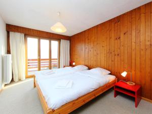 um quarto com uma cama grande com uma parede de madeira em Apartment Porthos 37 by Interhome em Verbier