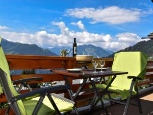 a table and chairs on a balcony with a bottle of wine at Apartment Porthos 37 by Interhome in Verbier