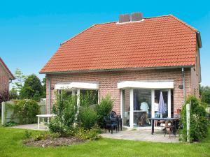 a red roofed house with a table and chairs at Holiday Home Tossens-5 by Interhome in Butjadingen OT Tossens