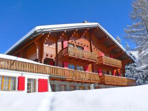 ein großes Holzgebäude mit Balkon im Schnee in der Unterkunft Apartment Rousserolles rez gauche by Interhome in Verbier