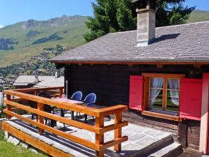 a house with a deck with two chairs on it at Chalet La Pive by Interhome in Verbier