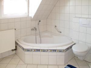 uma casa de banho branca com uma banheira e um WC em Apartment Marianne by Interhome em Hooksiel