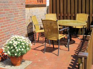 eine Terrasse mit einem Tisch, Stühlen und einer Pflanze in der Unterkunft Apartment Alte Molkerei-2 by Interhome in Friederikensiel