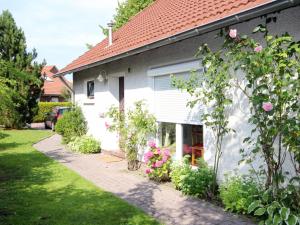 a white house with pink flowers in the yard at Holiday Home Mee - hrzeit - HOK106 by Interhome in Hooksiel