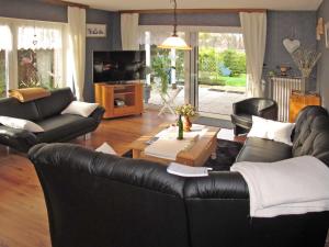 a living room with a black leather couch and a table at Holiday Home Lilly by Interhome in Osteel +14 photos