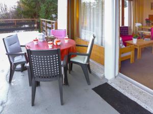 czerwony stół i krzesła na werandzie ze stołem i krzesłami w obiekcie Apartment Yuca B-2 by Interhome w mieście Crans-Montana