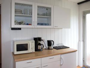 eine Küche mit weißen Schränken und einer Mikrowelle auf der Theke in der Unterkunft Holiday Home Osterkamp by Interhome in Friederikensiel