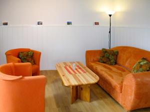 ein Wohnzimmer mit zwei orangenen Stühlen und einem Couchtisch in der Unterkunft Holiday Home Osterkamp by Interhome in Friederikensiel