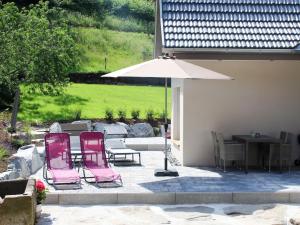 a patio with two pink chairs and an umbrella at Holiday Home am Bächle by Interhome in Hofstetten