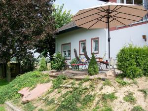 ein Haus mit einem Tisch und einem Sonnenschirm in der Unterkunft Apartment Vogesenblick by Interhome in Heiligenzell