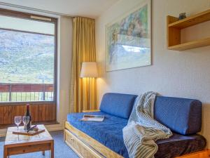 uma sala de estar com um sofá azul e uma janela em Apartment Les Tommeuses - Val Claret-19 by Interhome em Tignes