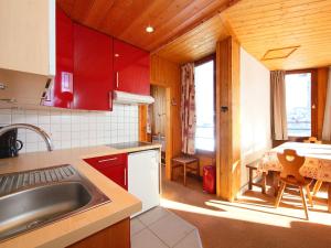 a kitchen with red cabinets and a table with a dining room at Apartment Les Hauts du Val Claret-6 by Interhome in Tignes