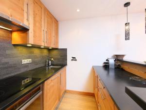 a kitchen with wooden cabinets and a black counter top at Apartment Les Hauts du Val Claret - Val Claret-17 by Interhome in Tignes