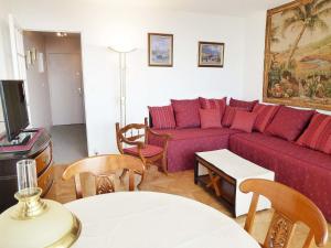 Una sala de estar con un sofá rojo y un televisor. en Studio Le Parc de La Jacotte-3 by Interhome, en Trouville-sur-Mer