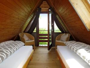 two beds in a wooden room with windows at Holiday Home Svea by Interhome in Wilhelmsdorf