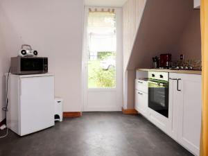 PlozévetにあるHoliday Home Les Blés - PZV108 by Interhomeの白いキャビネット、電子レンジ、窓付きのキッチン