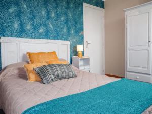 PlozévetにあるHoliday Home Les Blés - PZV108 by Interhomeの青い壁のベッドルーム1室(オレンジ色の枕付きのベッド1台付)