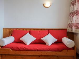a red couch with two white pillows on it at Apartment Home Club-1 by Interhome in Tignes
