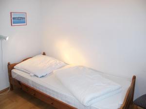 a bed with white sheets on it in a room at Apartment Juliusruh-2 by Interhome in Juliusruh +8 photos