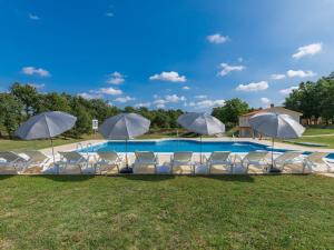 a group of chairs and umbrellas next to a pool at Apartment Macini - ROJ465 by Interhome in Žminj