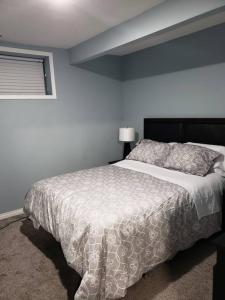 Cozy Two Bedroom Guest Suite in NW في كالغاري: غرفة نوم بسرير لحاف أبيض ونافذة