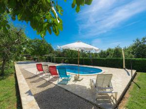 a group of chairs and an umbrella next to a pool at Holiday Home Jadranka - ROJ416 by Interhome in Žminj