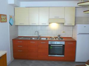 cocina con armarios de madera, fregadero y nevera en Apartment A 3 by Interhome, en Nerano