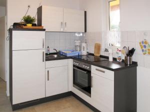 a kitchen with white cabinets and black counter tops at Holiday Home Ella by Interhome in Zinnowitz