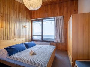 una camera da letto con un letto con cuscini blu e una finestra di Apartment Le Curling B-22 by Interhome a Tignes