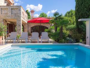 a swimming pool with chairs and a red umbrella at Holiday Home Villa Crispo - MDN119 by Interhome in Medulin