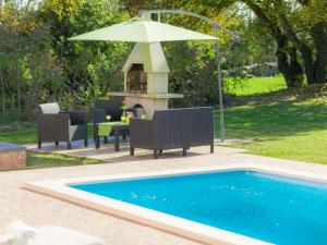 a swimming pool with a table and an umbrella at Holiday Home Vita - RCA406 by Interhome in Marčana