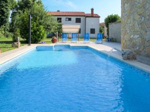 a swimming pool with blue chairs and a house at Holiday Home Pinezici - RCA151 by Interhome in Marčana