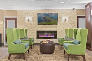 una sala de espera con sillas verdes y chimenea en Comfort Inn Syosset-Long Island, en Syosset