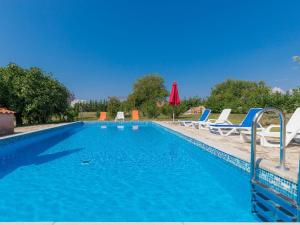 a swimming pool with lounge chairs and a umbrella at Holiday Home Danijela - ROJ406 by Interhome in Žminj