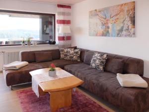 ein Wohnzimmer mit einem braunen Sofa und einem Tisch in der Unterkunft Apartment Schwarzwaldblick-19 by Interhome in Obertal