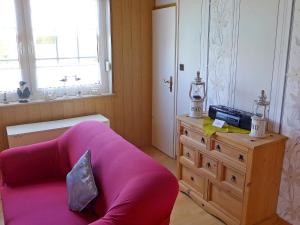 a living room with a pink couch and a dresser at Holiday Home Gila by Interhome in Dornumersiel +9 photos