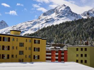 a building with a snow covered mountain in the background at Apartment Chesa Fleury by Interhome in St. Moritz