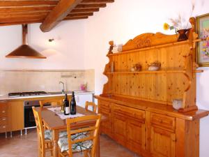 a kitchen with wooden cabinets and a table with wine bottles at Apartment I Ceneruzzi-2 by Interhome in Gambassi Terme