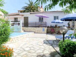 a house with a swimming pool and two umbrellas at Holiday Home Franko 1 - MDN182 by Interhome in Ližnjan