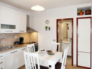 eine Küche mit einem weißen Tisch und weißen Schränken in der Unterkunft Apartment Borovina - KOR205 by Interhome in Prigradica