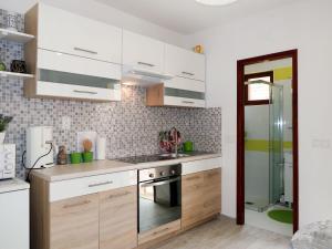 eine Küche mit weißen Schränken und einer Glasdusche in der Unterkunft Apartment Borovina - KOR204 by Interhome in Prigradica