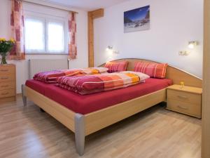 ein Schlafzimmer mit einem großen Bett mit roter Bettwäsche in der Unterkunft Apartment Fürderer by Interhome in Eisenbach