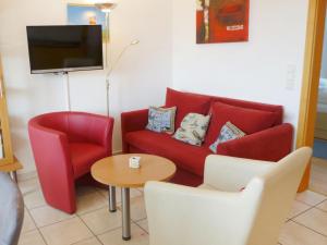 ノルトダイヒにあるApartment Frisiastrasse-3 by Interhomeのリビングルーム(赤いソファ、椅子2脚、テーブル付)
