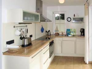 a kitchen with white cabinets and a wooden counter top at Holiday Home Katja by Interhome in Ostseebad Karlshagen