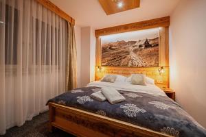 a bedroom with a bed with a painting on the wall at Apartament Podwika in Zakopane