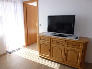 a flat screen tv sitting on top of a wooden cabinet at Apartment Schwarzwaldblick-11 by Interhome in Obertal +3 photos